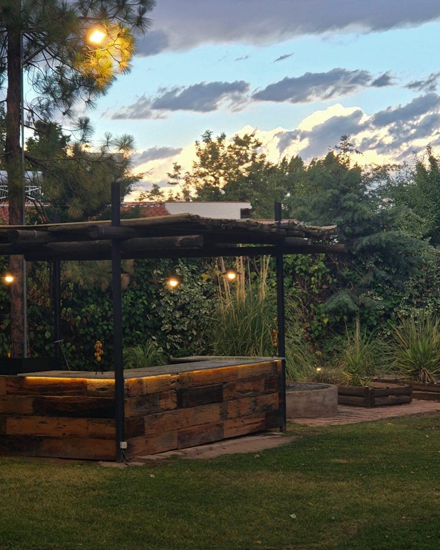 La barra bajo la pérgola al atardecer, con las luces encendidas y el cielo todavía claro