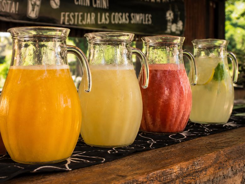 Cuatro jarras de jugos naturales y limonada de la casa, alineadas sobre la barra