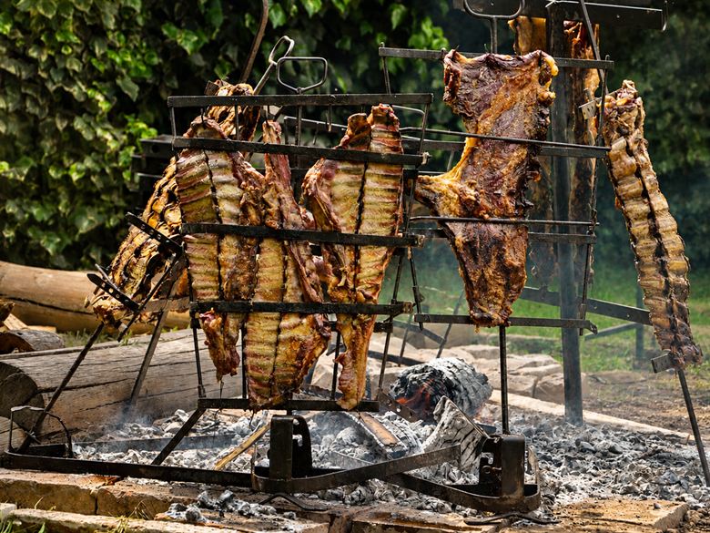 Ocho costillares en cruz alrededor del fogón, dorándose sobre las brasas