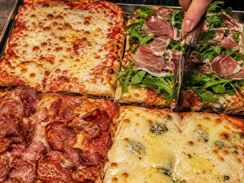 Las cuatro pizzas recién cortadas: mozzarella, jamón crudo con rúcula, cantimpalo y cuatro quesos