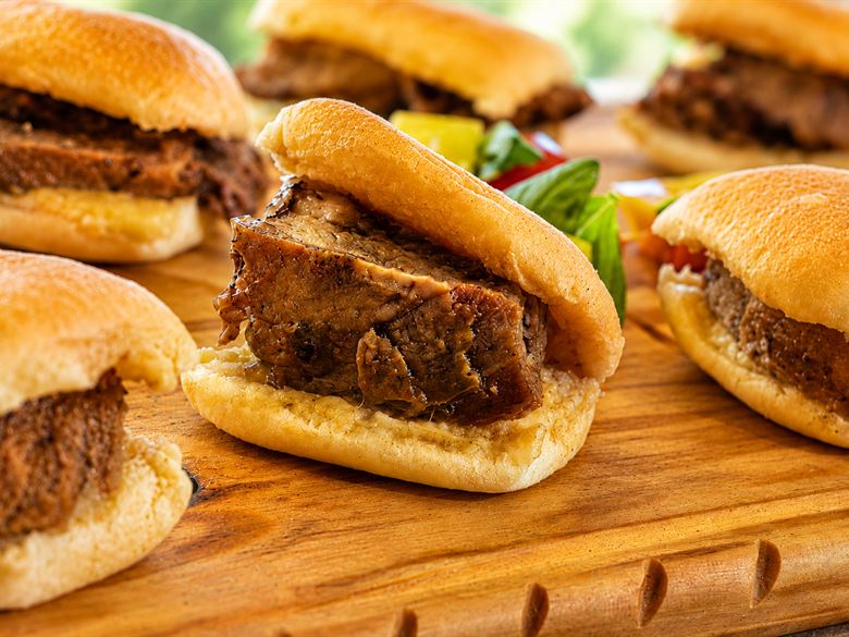 Los sándwiches de vacío a la llama en pan casero, recién armados sobre la tabla de madera